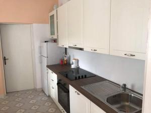 a kitchen with white cabinets and a sink and a refrigerator at Apartmani Rija 3 in Pag