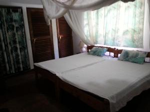a bedroom with a bed with a window with white curtains at Sunset Villa Eco Friendly House in Kilifi +58 photos