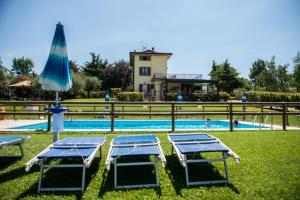 einen Pool mit 2 Stühlen und einem Sonnenschirm in der Unterkunft Agriturismo Il Giardino Degli Ulivi in Lazise