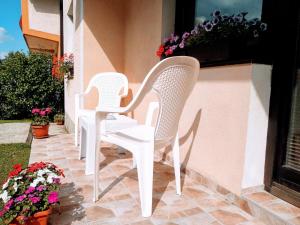 Dos sillas blancas sentadas en un patio con flores en Apartment Knez en Kolašin