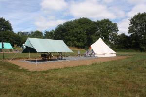 two tents in a field with trees in the background at The Valley Bell Tents, Bring Your Own Bedding in Amroth