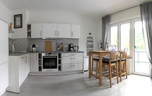 eine Küche mit weißen Schränken sowie einem Tisch und Stühlen in der Unterkunft Haus Josef Klotten in Klotten