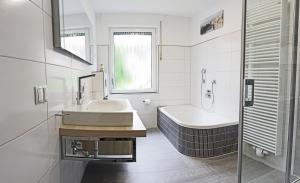 ein weißes Badezimmer mit einer Badewanne und einem Waschbecken in der Unterkunft Haus Josef Klotten in Klotten