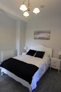 a bedroom with a large white bed with black pillows at Farfield in Threshfield