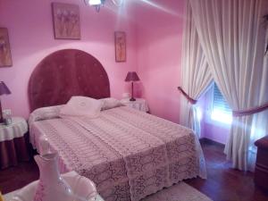 a pink bedroom with a bed and a window at Plaza del Pacifico La Bazana in Jerez de los Caballeros