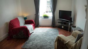 un soggiorno con sedia rossa e TV di Danny’s Place a Londonderry