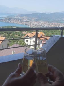 una persona che tiene un bicchiere di fronte a una vista di Ohrid Sunset Apartments Velestovo a Ohrid