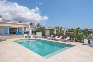 a swimming pool with chairs and a house at Villa Luna in Sa Torre