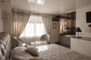a bedroom with a bed and chairs and a kitchen at Jacuzzi Apartamentai Relaks in Klaipėda