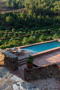 a swimming pool with two picnic tables next to a mountain at Terra Dominicata - Hotel & Winery - Adults Only in Escaladei