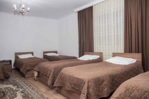 a room with three beds and a chandelier at Sweet House GH in Karakol