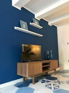 a living room with a television on a blue wall at Be Blu Apartment in Naples