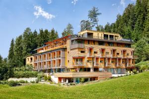 a large building on top of a hill with trees at Naturhotel Die Waldruhe GmbH in Chienes