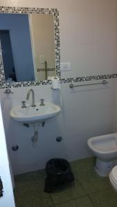 
a bathroom with a toilet, sink and mirror at Hotel Dallas Center in Mar del Plata
