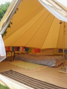 een grote gele tent met een bed erin bij The Valley Bell Tents, Bring Your Own Bedding in Amroth