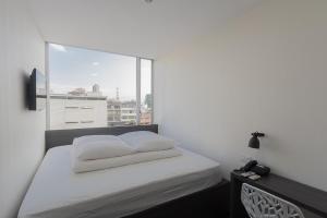 1 dormitorio con cama blanca y ventana grande en YU! Smarthotels, en Guayaquil