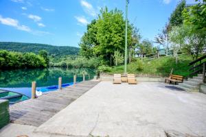 a dock with two benches and a lake at Apartments River Una 3 in Bihać