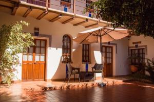 a patio with an umbrella and chairs and a table at La Escondida Hostal in Sucre