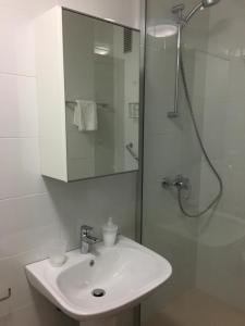 y baño blanco con lavabo y ducha. en Apartamento frente al mar, en Ceuta