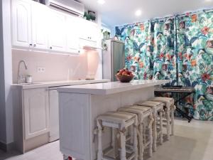 una cocina con armarios blancos y una barra con taburetes en Aloha Paraíso, en Torremolinos