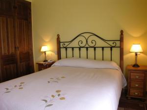 a bedroom with a large white bed with two lamps at Hotel Rural La Dehesilla in Barajas de Gredos