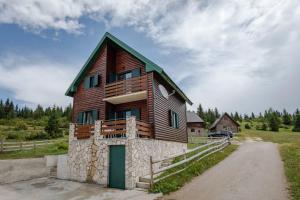 a wooden house with a green door on a dirt road at Guest house Heaven in Žabljak