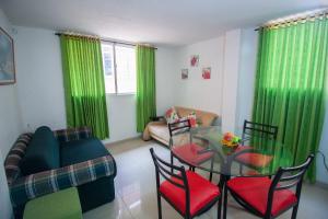 sala de estar con cortinas verdes, mesa de cristal y sillas en El Velero Apartamentos By DANP en Santa Marta