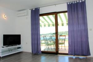 a living room with purple curtains and a tv at Apartmani TEO in Tisno