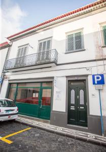 ポンタ・デルガダにあるCasa da Avó Guidaの緑の扉と駐車場のある白い建物