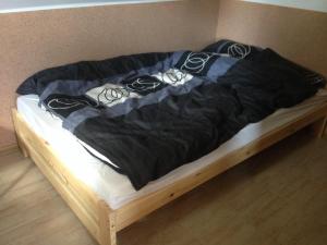 a bed with a black comforter on top of it at Agroturystyka 'Pod dębem' in Giżycko