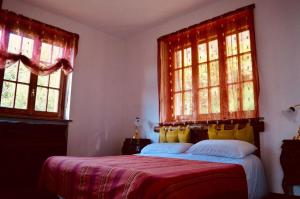 Gold Cave casa vacanze relax nel bosco appartamenti في Pessinetto: غرفة نوم بسرير وبطانية حمراء ونوافذ