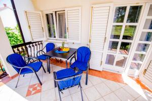 une terrasse couverte avec des chaises bleues et une table. dans l'établissement Apartman Katarina, à Trebinje