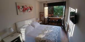 a bedroom with a white bed and a balcony at Apartamento ENTREVIÑAS en el corazón de La Rioja in Fuenmayor