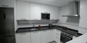 a white kitchen with a sink and a microwave at Apartamento ENTREVIÑAS en el corazón de La Rioja in Fuenmayor