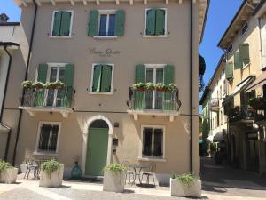 een gebouw met groene luiken en tafels en stoelen bij Casa Oreste in Lazise