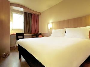 a hotel room with a large white bed and a window at ibis Porto Centro São Bento in Porto