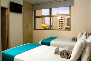 a hotel room with two beds and a window at Hotel Med Barranquilla Centro in Barranquilla