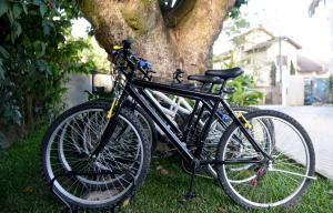 uma bicicleta preta estacionada ao lado de uma árvore em Le Garden Pousada Boutique em Penedo