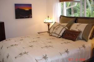 ein Schlafzimmer mit einem Bett mit Tagesdecke und Vögeln darauf in der Unterkunft Bamboo Valley Inn in Haiku
