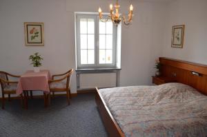 a bedroom with a bed and a table and a window at Hotel Kinnen in Berdorf