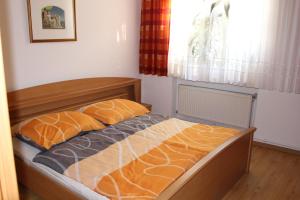 a bedroom with a bed with orange and gray sheets at Appartement "Blumengassl" in Mörbisch am See