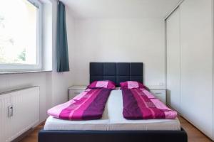 a bedroom with a bed with pink pillows on it at 70 square m with balcony+parking+AC in Ljubljana