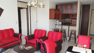 a living room with red chairs and a kitchen at Apartment business/airport area Guatemala City in Guatemala