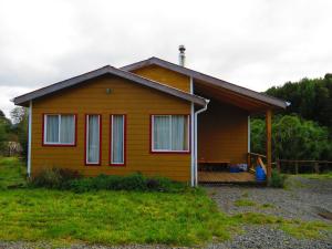 a small house with a porch on a field at Cabañas Río Quemille in Huillinco