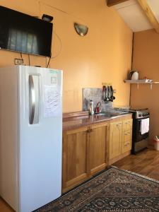 a kitchen with a white refrigerator and a sink at Cabañas Río Quemille in Huillinco