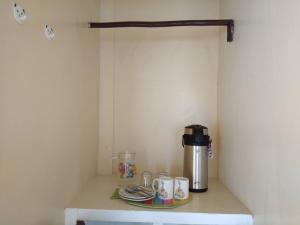 a coffee maker sitting on a shelf with cups and plates at Nelmann's Nipa Huts in San Vicente