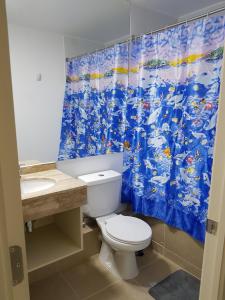 La salle de bains est pourvue de toilettes et d'un rideau de douche bleu. dans l'établissement Departamento Laguna Bahía Algarrobo, à Algarrobo