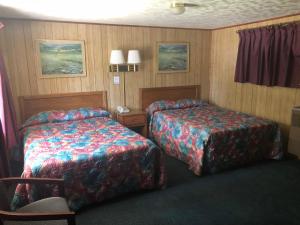 una camera d'albergo con due letti e una sedia di Elmwood Motor Lodge a Boscawen