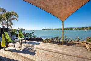 een terras met stoelen en uitzicht op het water bij Mapua Wharfside Apartments in Mapua