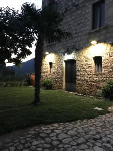- un bâtiment en pierre avec un palmier en face dans l'établissement Casa Sarlo, à Petina